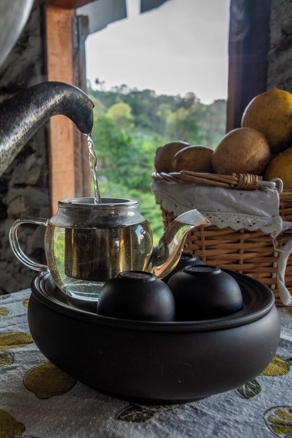 A teapot on a table with a basket of bread and a window view. - Doi Inthanon Tea Farmstay (Mae Wang)