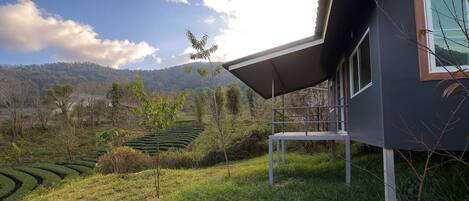 Una casa moderna con balcón, rodeada de un paisaje verde exuberante y vistas a campos escalonados.