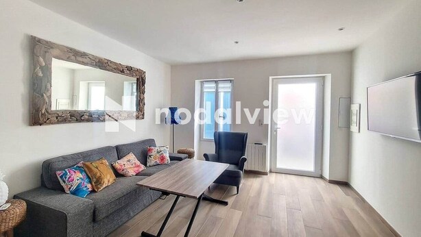 Ein modernes Wohnzimmer mit einem grauen Sofa, einem Holztisch und einem großen Spiegel.