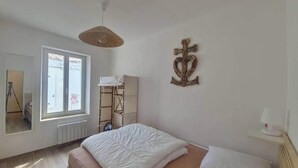 Ein Schlafzimmer mit einem Bett, einem Fenster, einem Heizkörper, einer Holzleiter und einer Wanddekoration.