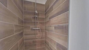 Eine Dusche mit Handbrause und Armatur an der Wand.