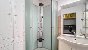 A bathroom with a shower, a sink, and a mirror. - Stud Résidence le trident 63 (Saintes-Maries-de-la-Mer)