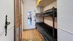 A narrow hallway with a wooden door, a bunk bed, and a view into another room. - Stud Résidence le trident 63 (Saintes-Maries-de-la-Mer)