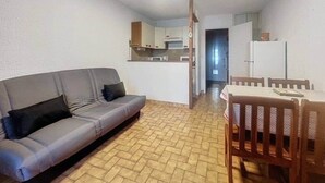 A compact living space with a sofa, dining table, and kitchen area. - Stud Résidence le trident 63 (Saintes-Maries-de-la-Mer)