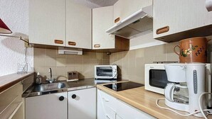 A compact kitchen with white cabinets, a microwave, a toaster, and a coffee maker. - Stud Résidence le trident 63 (Saintes-Maries-de-la-Mer)
