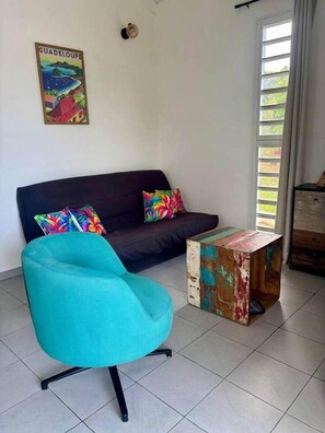 A living room with a dark sofa, colorful pillows, a turquoise armchair, and a rustic coffee table.