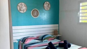 Une chambre à coucher avec un mur d’accent de couleur turquoise, un lit recouvert d’une couvre-lit à rayures et des œuvres d’art décoratives accrochées au mur.