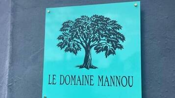 Un cartello con un albero e il testo "LE DOMAINE MANNOU" su sfondo color acquamarina.