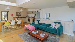 A spacious living area with a wooden dining table, teal sofa, and a wooden coffee table. - 4 The Stoneyard (Bath)