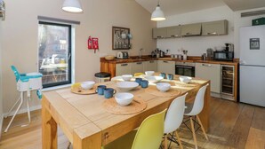 A modern kitchen with wooden countertops, a dining table set with bowls and cups, and pendant lighting. - 4 The Stoneyard (Bath)