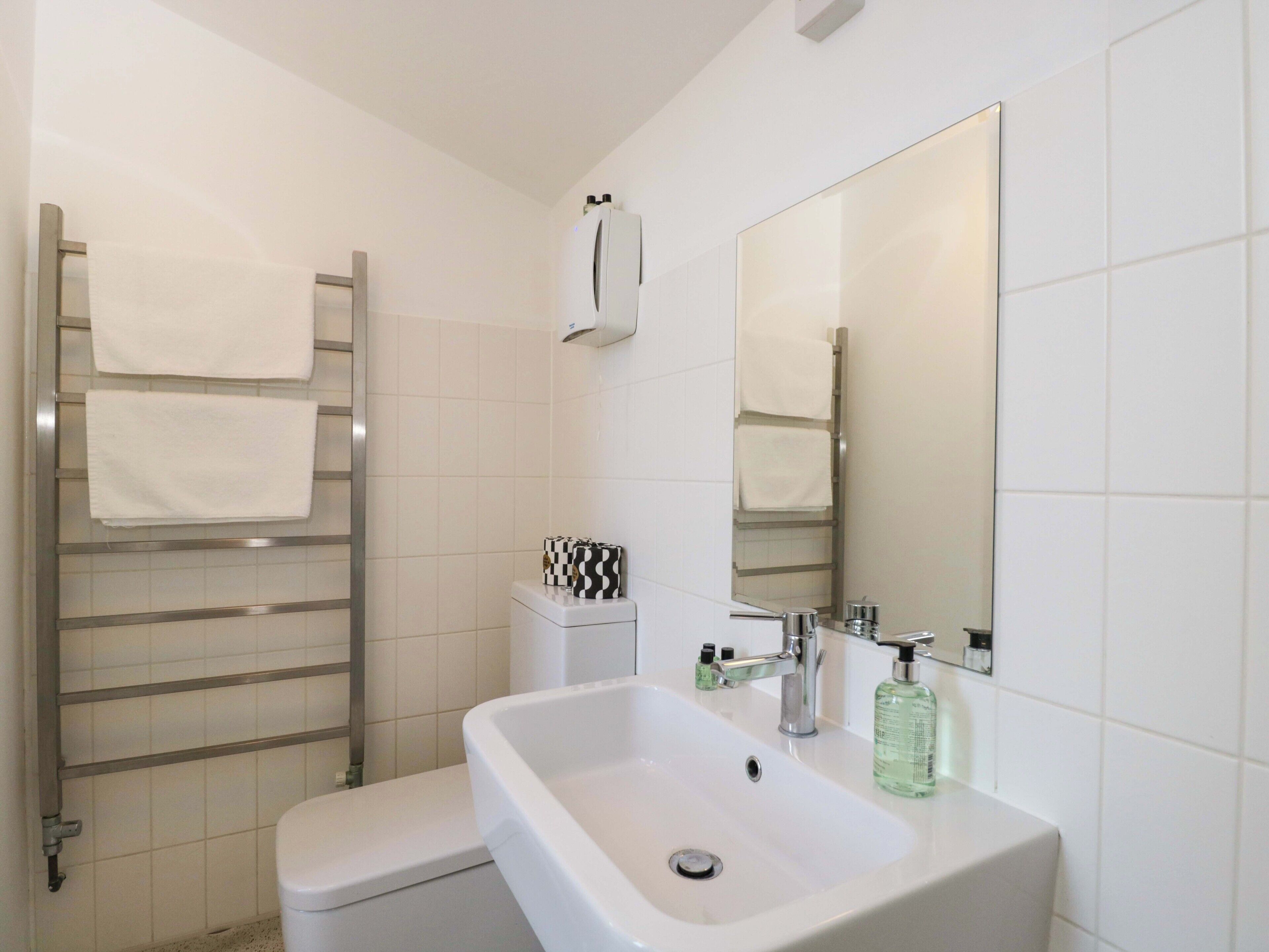 Une salle de bain avec un lavabo blanc, un miroir, un porte-serviettes et des toilettes.