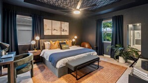 Un dormitorio moderno con una cama grande, lámparas de noche, un escritorio y un espejo.