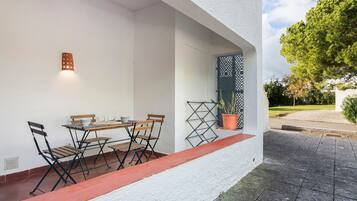 A patio with a table and chairs, a potted plant, and a door with a lattice design.