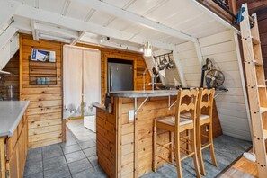 Cocina compacta con armarios de madera, refrigerador integrado y barra con taburetes.