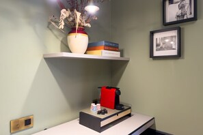 A room with a shelf holding books and a vase with dried flowers, a coffee machine, and a framed picture on the wall. - GuestHost - In the heart of Brera, in a 20th-century Art Nouveau building on the 1st floor with elevator is the newly renovated double room with large bathroom, a cozy double bed, air conditioning, wifi, mini-bar, coffee maker, smart TV, bath linens, ill (Milan)