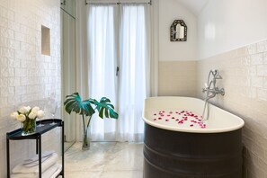 A bathroom with a bathtub, a mirror, a plant, and a tray with flowers and glasses. - GuestHost - In the heart of Brera, in a 20th-century Art Nouveau building on the 1st floor with elevator is the newly renovated double room with large bathroom, a cozy double bed, air conditioning, wifi, mini-bar, coffee maker, smart TV, bath linens, ill (Milan)