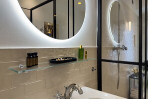A modern bathroom with a glass shelf, a large mirror, and a shower area.