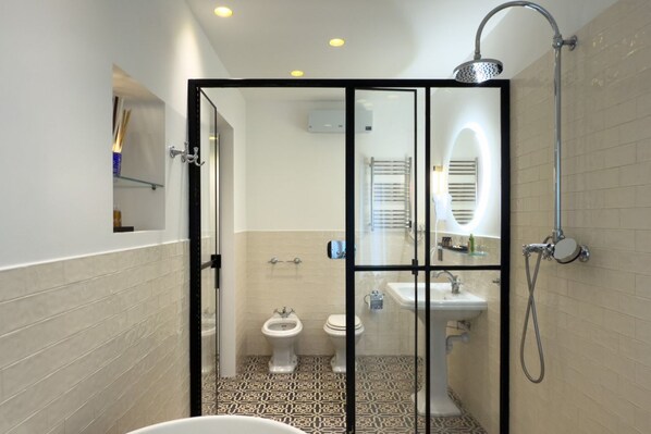 A modern bathroom with a glass-enclosed shower, a white sink, and a bidet.