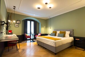 A hotel room with a bed, desk, chairs, and a view of the outside.