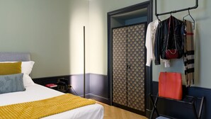 A hotel room with a bed, a wardrobe, a hanging rack with bags, and a shoe rack. - GuestHost - In the heart of Brera, in a 20th-century Art Nouveau building on the 1st floor with elevator is the newly renovated double room with large bathroom, a cozy double bed, air conditioning, wifi, mini-bar, coffee maker, smart TV, bath linens, ill (Milan)