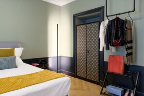 A hotel room with a bed, a wardrobe, a hanging rack with bags, and a shoe rack. - GuestHost - In the heart of Brera, in a 20th-century Art Nouveau building on the 1st floor with elevator is the newly renovated double room with large bathroom, a cozy double bed, air conditioning, wifi, mini-bar, coffee maker, smart TV, bath linens, ill (Milan)