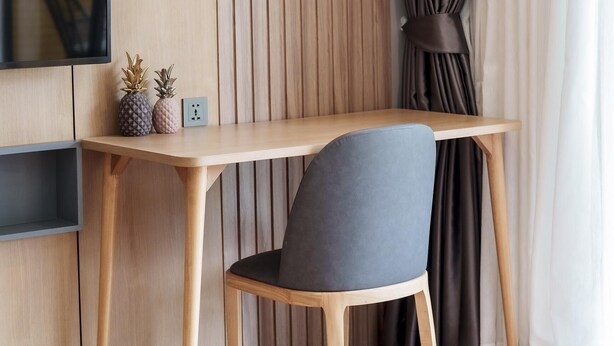 A modern room with a wooden desk, a chair, a television mounted on the wall, and a window with curtains. - Beachfront 1524 Wyndham Gardens Condo Naithon (Sa Khu)