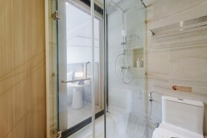 A modern bathroom with a glass shower enclosure, a toilet, and a handrail. - Wyndham Gardens 2413 Elegant Studio Forest View (Sa Khu)
