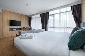 A modern hotel room with a large bed, a flat-screen TV mounted on the wall, and a window with curtains. - Wyndham Garden 1220 Modern Studio Next to Naitho (Sa Khu)