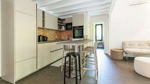 A modern kitchen with a dining area, a sofa, and a round ottoman.