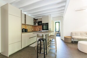 A modern kitchen with a dining area, a sofa, and a round ottoman.