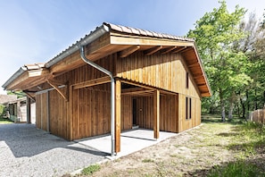 A wooden building with a sloped roof and a gravel driveway.