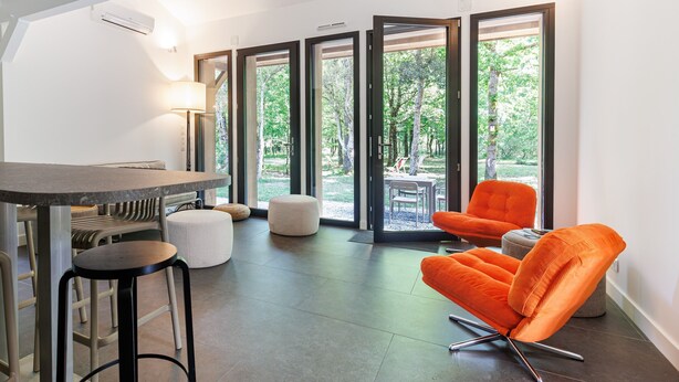 A modern interior with a dining area, a sofa, and a view through glass doors.