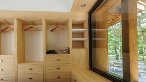 A bedroom with a large window, wooden wardrobe, and a bed.