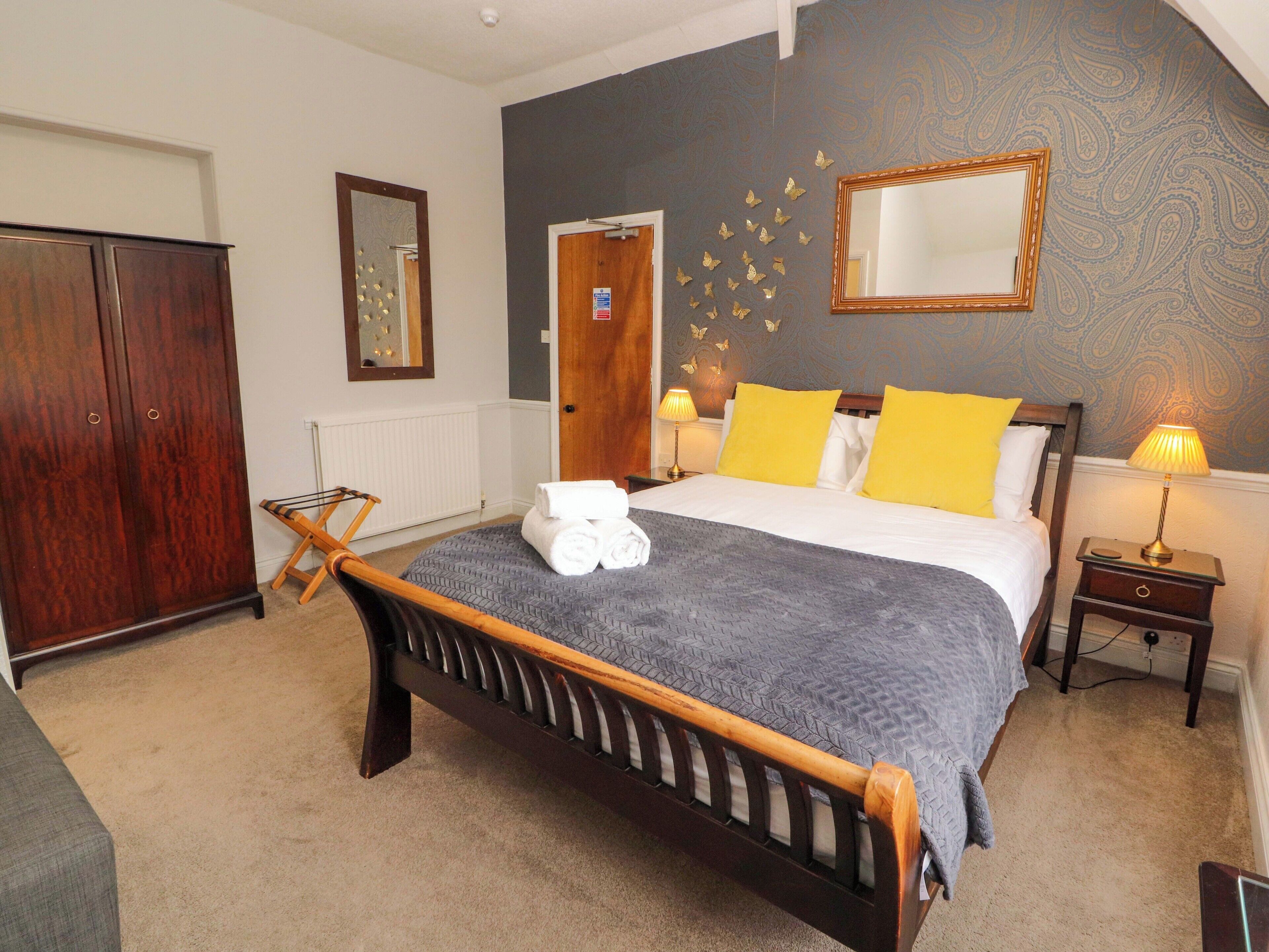 A bedroom with a bed, a wardrobe, a mirror, and a wall with butterfly decals.