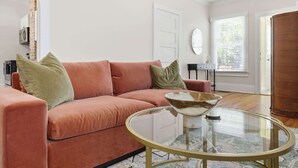 A living room with a pink sofa, a glass coffee table, and a door in the background. - The Pearl Unit A, Stay for 4 (St. Augustine)