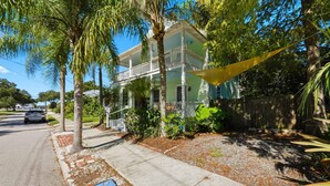 A two-story house with a balcony, surrounded by palm trees and a wooden fence. - The Pearl Unit A, Stay for 4 (St. Augustine)