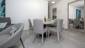 Et moderne spiseområde med et rundt bord, seks stole og en flaske champagne.