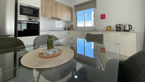 A modern kitchen with a glass dining table, stainless steel appliances, and a window with a view. - Vacation Home 'Lychee' with Private Pool, Wi-Fi and Air Conditioning (Las Palmas)