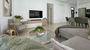 A modern living room with a flat-screen TV, sofas, a coffee table, and a dining area with chairs. - Vacation Home 'Lychee' with Private Pool, Wi-Fi and Air Conditioning (Las Palmas)