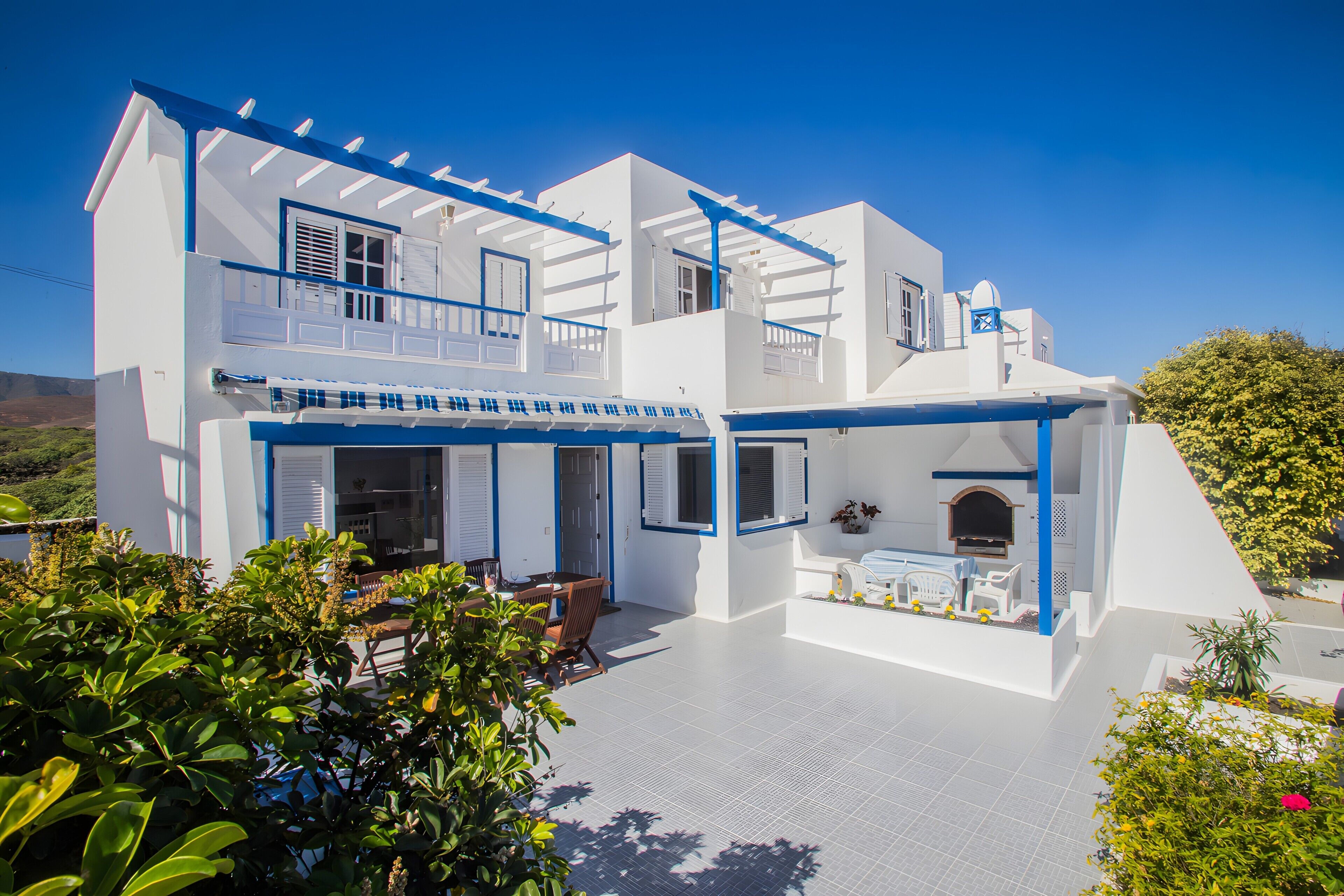 Un bâtiment blanc à deux étages, doté de balcons, d’un patio et d’un petit jardin.