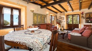 A rustic interior with a wooden dining table, a sofa, and a large vase.