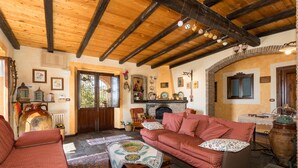 A cozy living room with a wooden ceiling, a fireplace, and a red sofa.