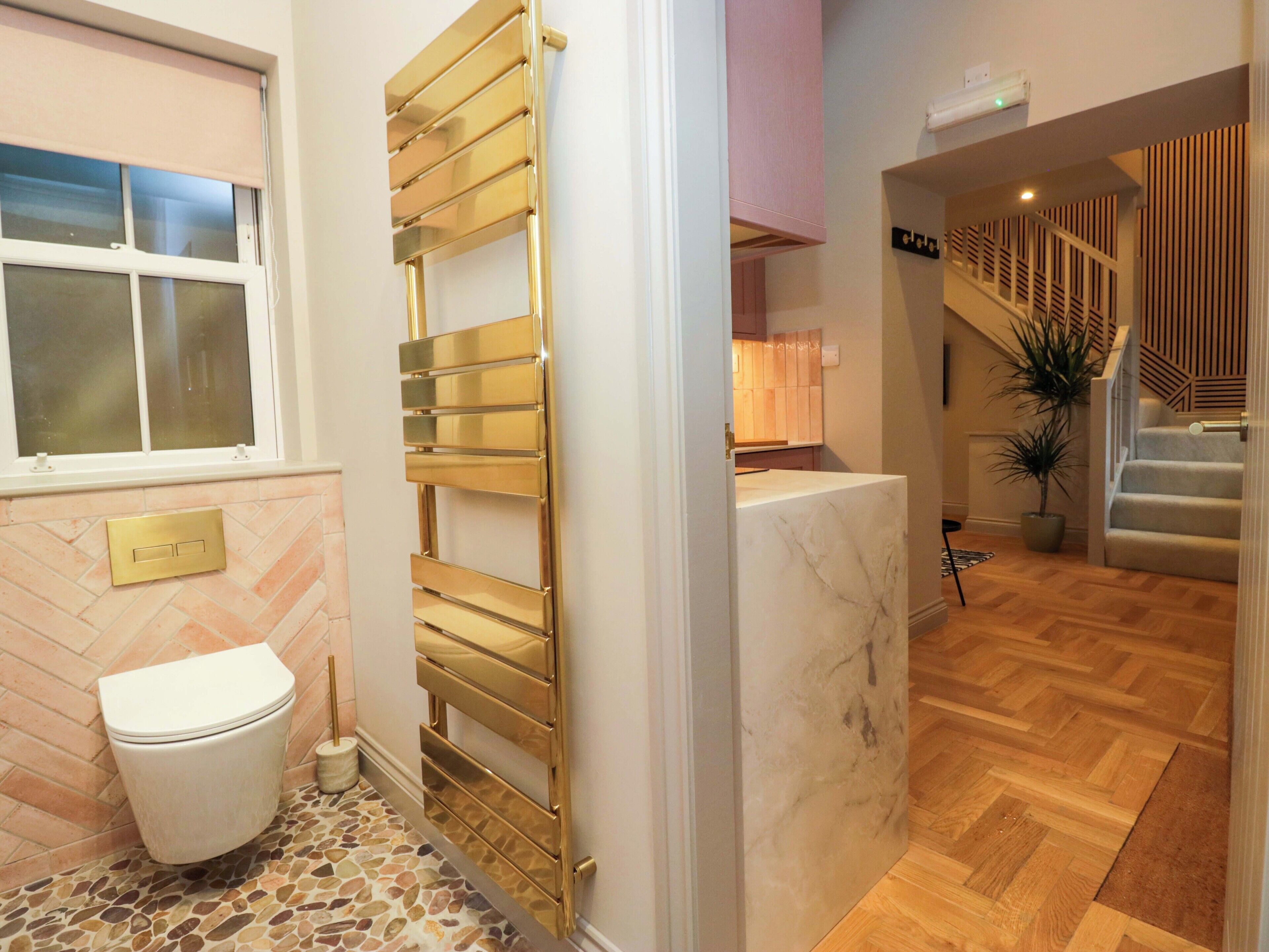 A bathroom with a white toilet, a gold towel warmer, and a marble sink.