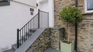 Un escalier avec un mur en pierre et un petit bac à fleurs.
