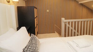 Une chambre à coucher comprenant un lit, une table de chevet, une lampe et un plafond en pente orné de lignes verticales.