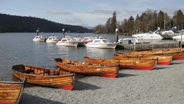 Un port de plaisance où plusieurs bateaux en bois sont amarrés sur la rive et où quelques bateaux à moteur sont à flot.