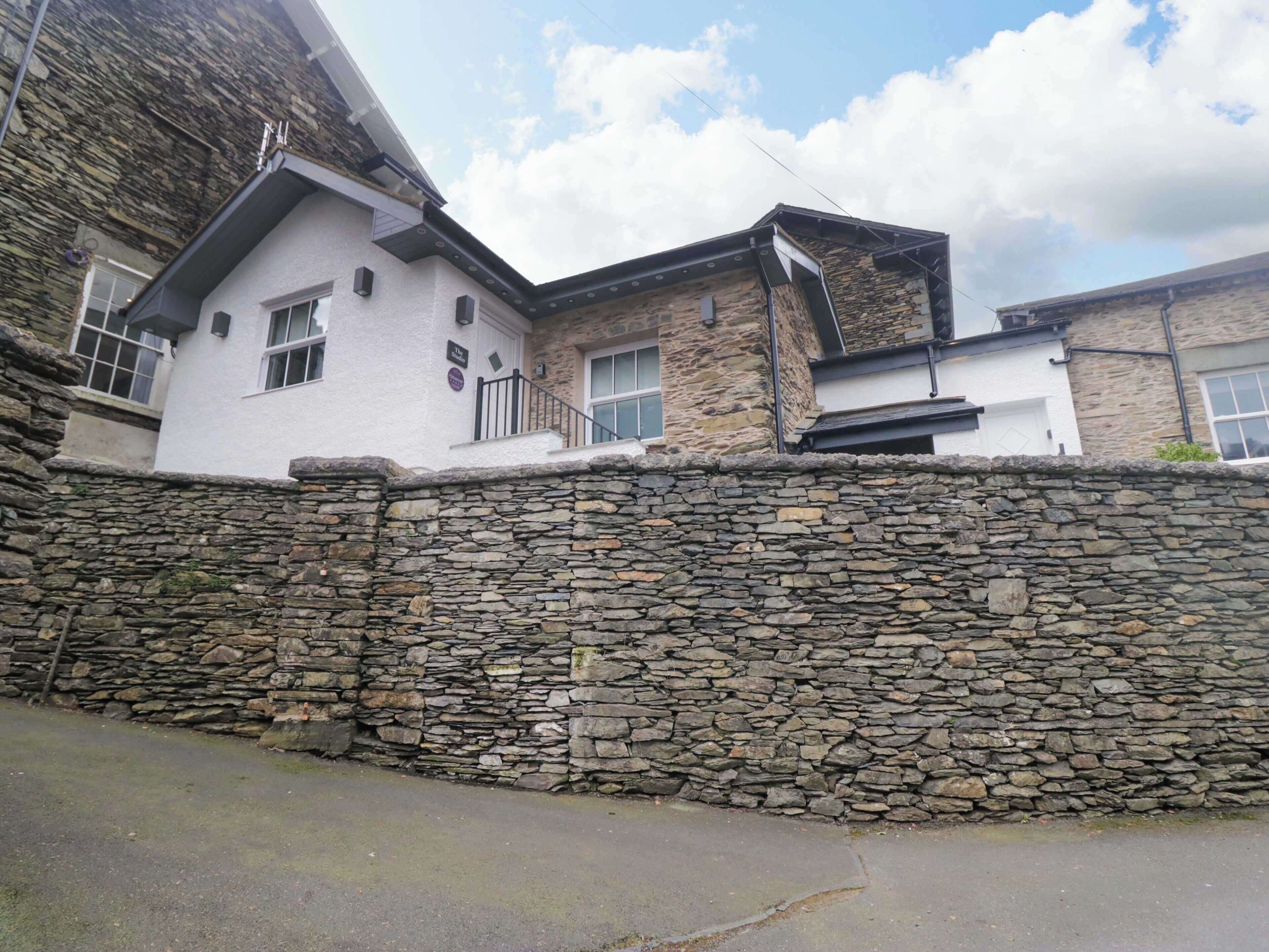 Un mur de pierre et un bâtiment à la façade blanche et à la partie supérieure en pierre.