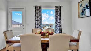 Un coin repas avec une table en bois, des chaises recouvertes d’un tissu beige et un centre de table floral.