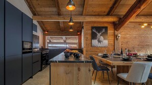 Una cucina moderna con isola centrale, travi in legno a soffitto e un'ampia finestra.