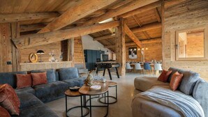 Un'ampia zona giorno con soffitto in legno, un divano, un tavolo da pranzo e una cucina sullo sfondo.